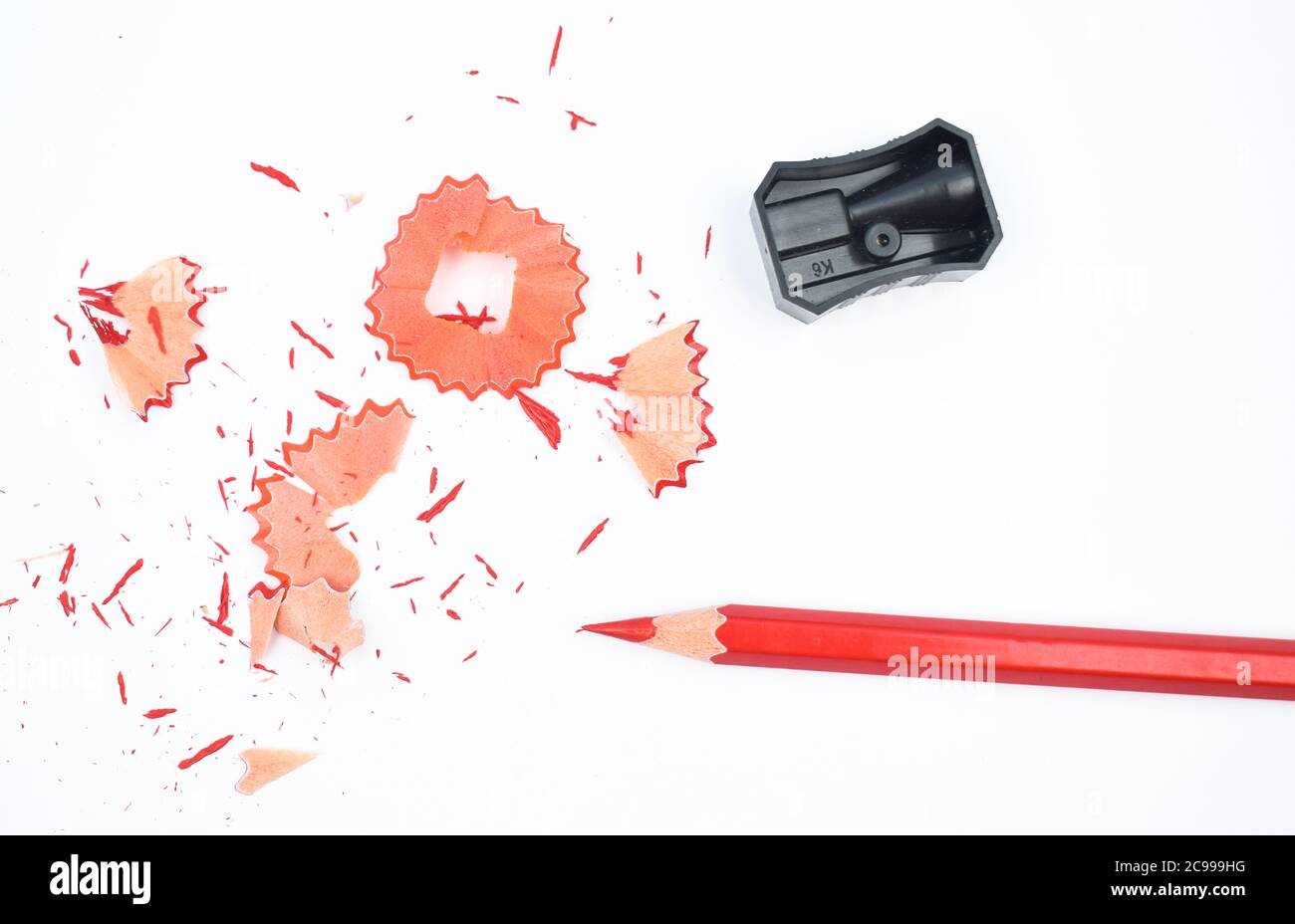 Certains matériaux d'étude contenant un crayon rouge et un taille-crayon en plastique noir isolé Banque D'Images