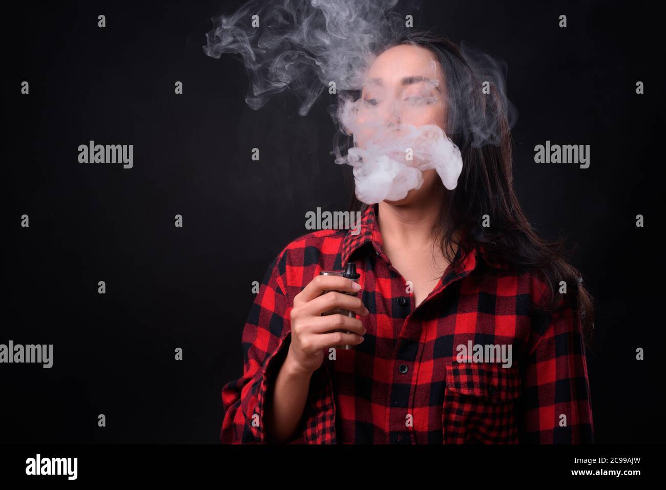 Jeune belle femme asiatique se vaporisant sur fond noir Banque D'Images