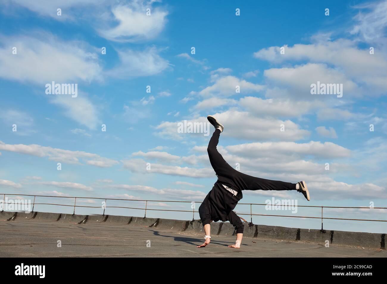 food Monopoly Moderator Danseuse asiatique de hip-hop vêtue d'un pantalon de sport noir,  sweat-shirt sautant dans l'air, faisant une marche arrière à l'extérieur  sur le toit au-dessus de bleu ciel arrière Photo Stock - Alamy