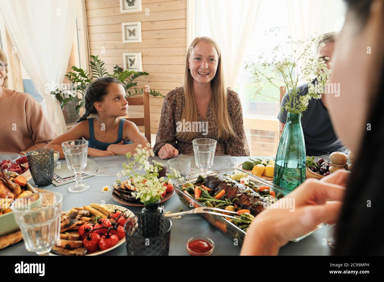 Bonne famille assise à table de fête et manger de délicieux plats à la maison Banque D'Images