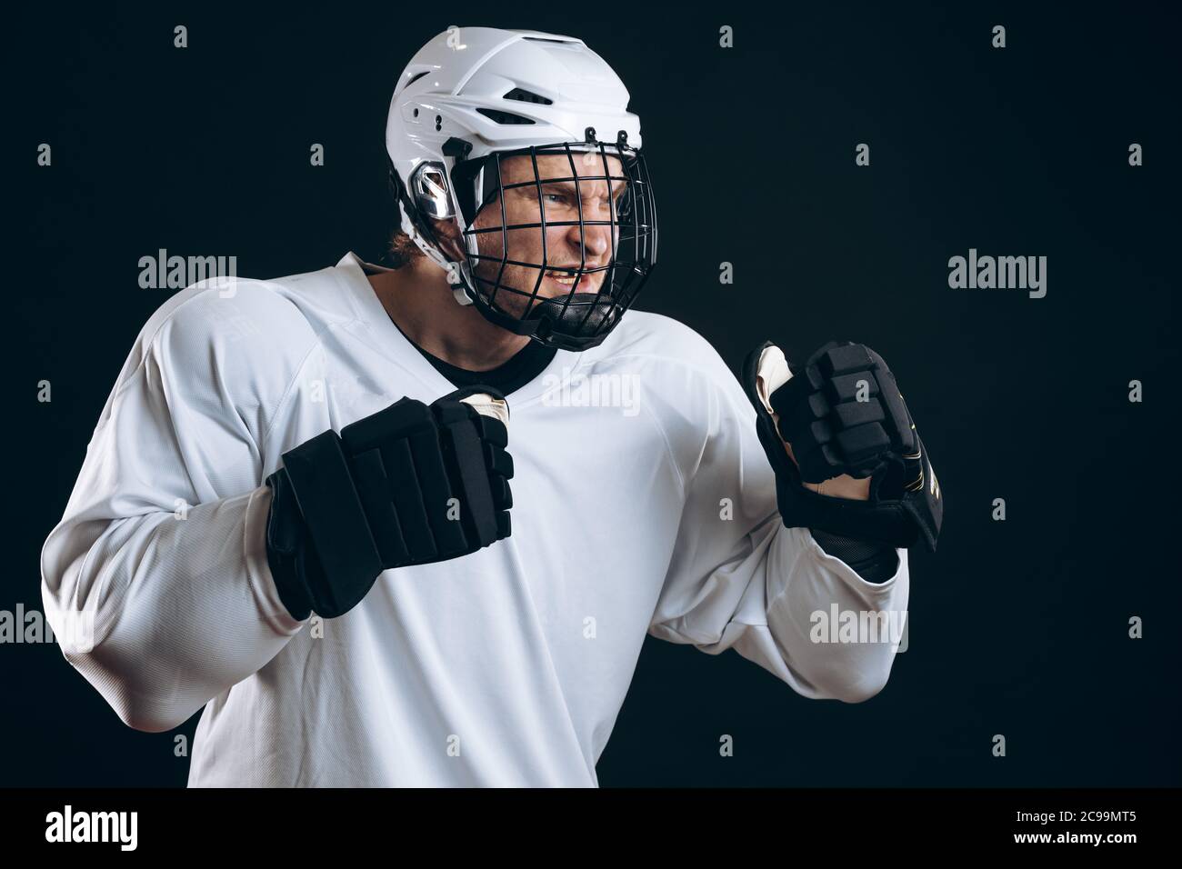 Portrait d'un joueur professionnel de hockey sur glace en vêtements de  sport blancs, debout sur une position défensive, à l'allure féroce, isolé  sur fond noir Photo Stock - Alamy