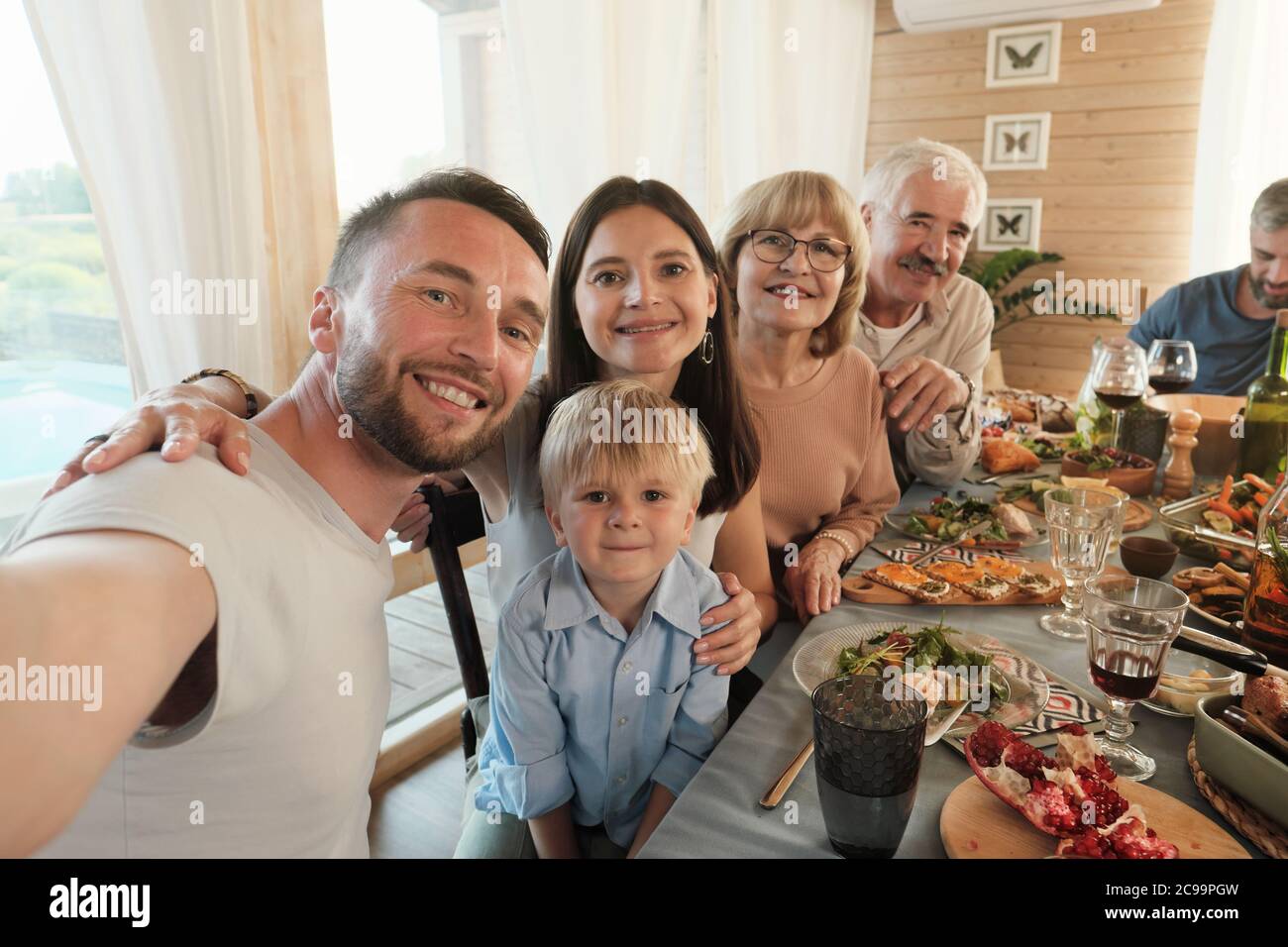 Portrait d'un homme mûr faisant le portrait de sa grande famille pendant qu'ils sont assis à la table pendant le dîner à la maison Banque D'Images