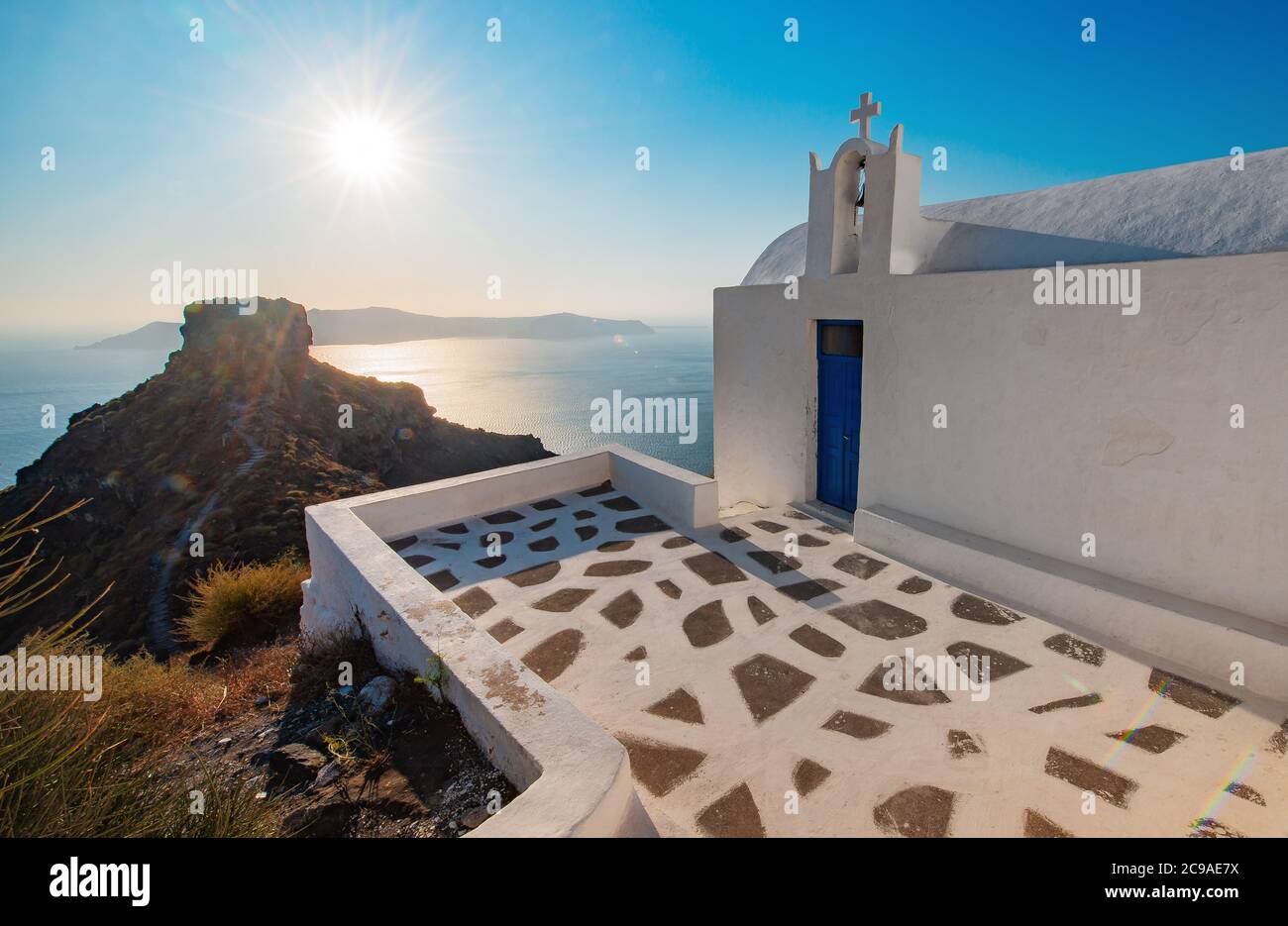 Coucher de soleil orange dans une église blanche avec un dor bleu à Skaros Rock à Santorini, Grèce Banque D'Images