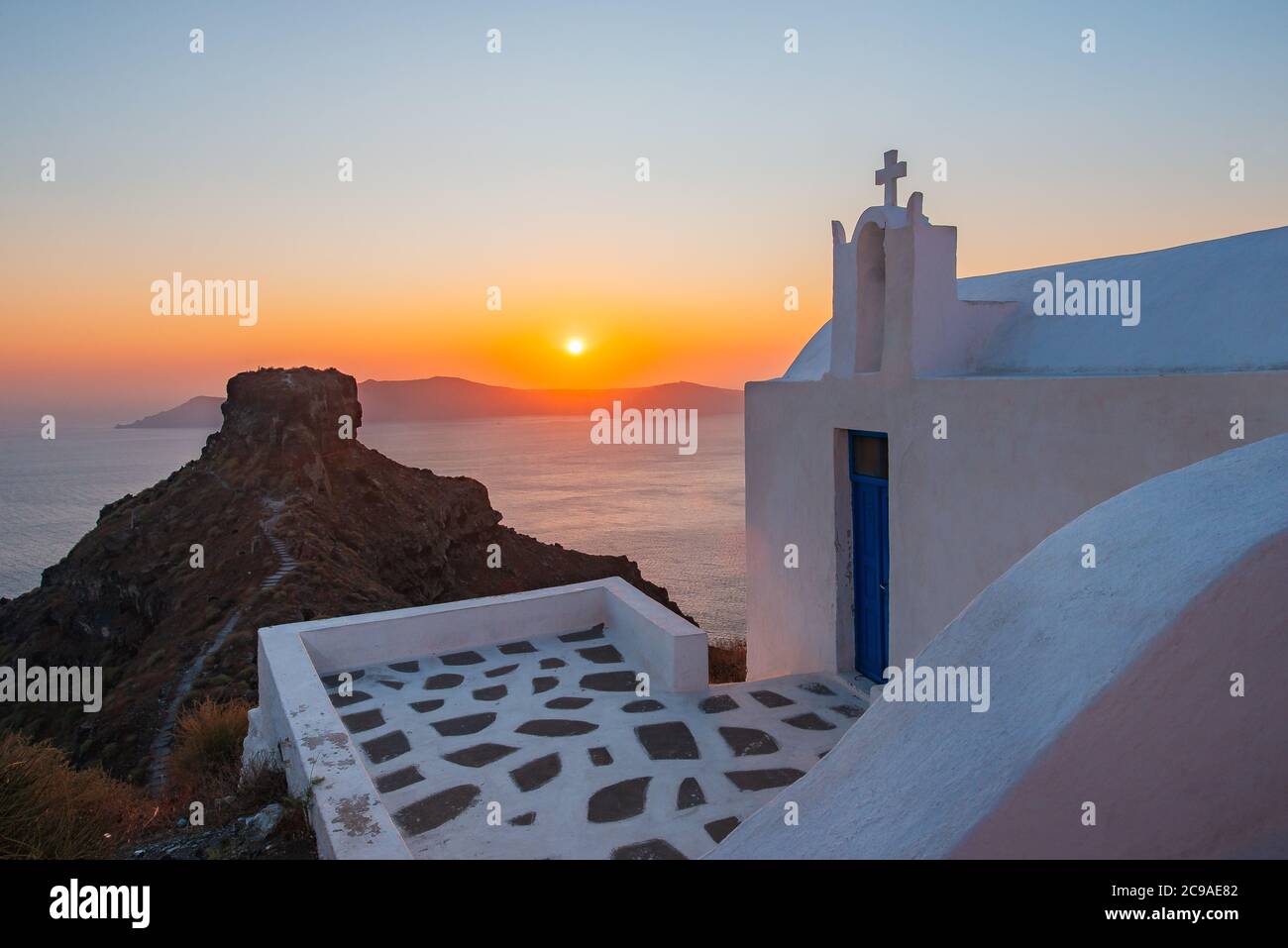 Coucher de soleil dans une église blanche de Santorin. Skaros Rock en arrière-plan. Endroit célèbre en Grèce Banque D'Images