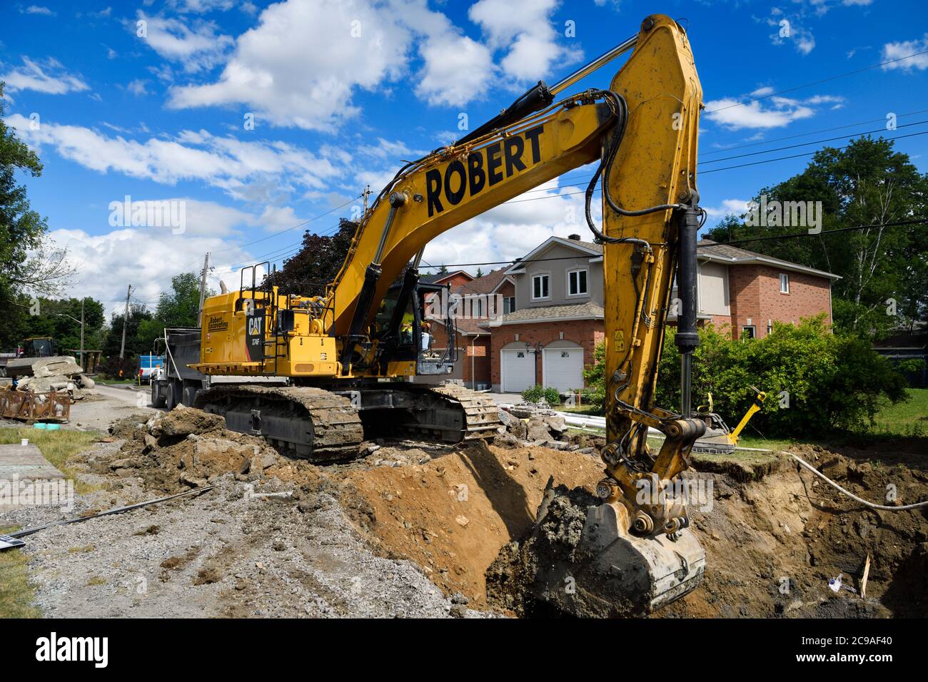 Pelle hydraulique creusant une tranchée pour de nouveaux égouts dans une rue résidentielle de Nepean, Ontario Banque D'Images