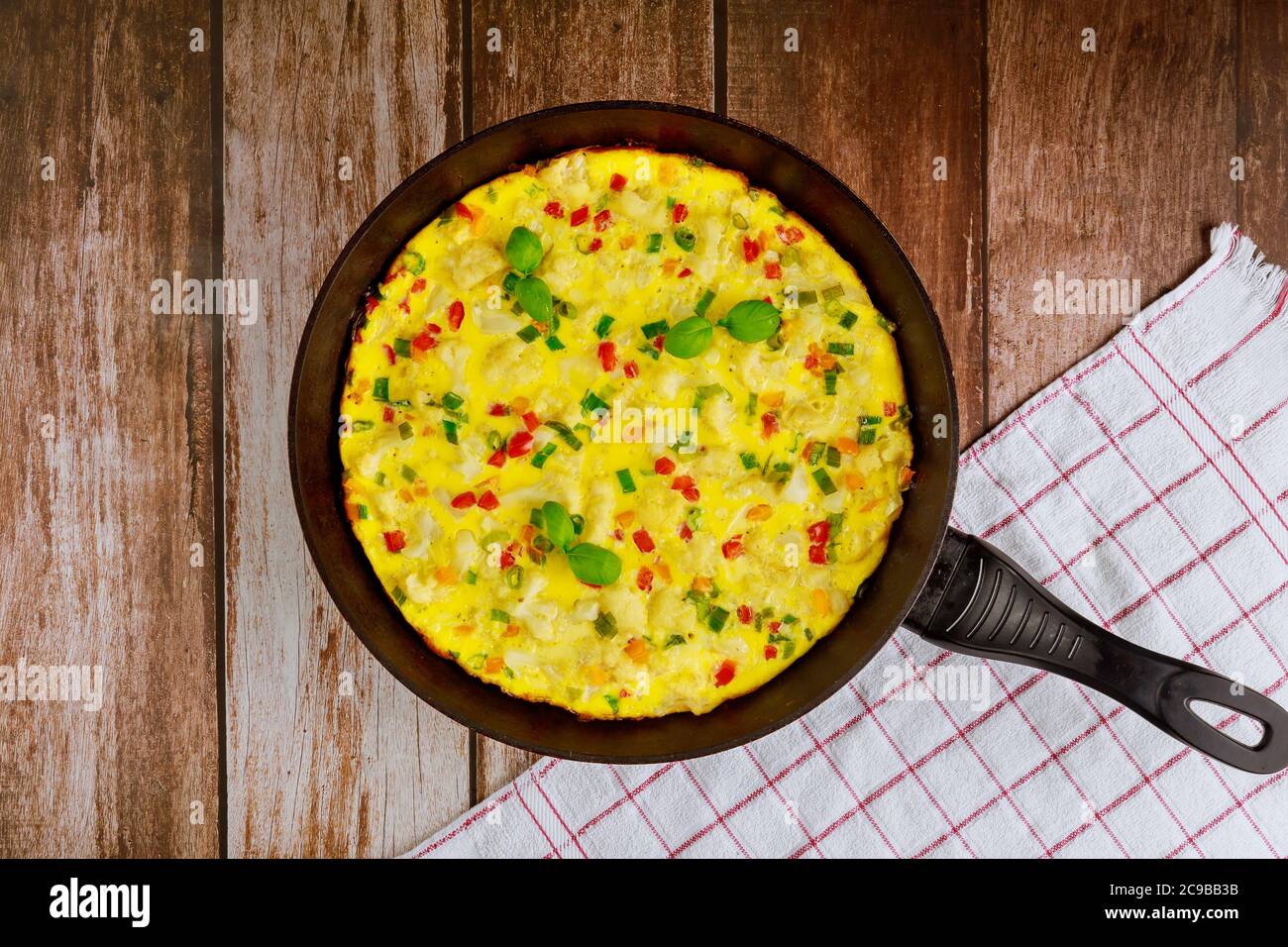 Frittata au fromage, chou-fleur, poivron vert et rouge dans une poêle à frire. Banque D'Images