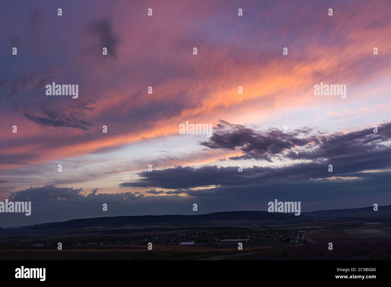 Magnifiques nuages roses au coucher du soleil sur le village. Ligne d'horizon basse. Paysage rural. Coucher de soleil d'été sur le village. Ciel violet crépuscule. Banque D'Images