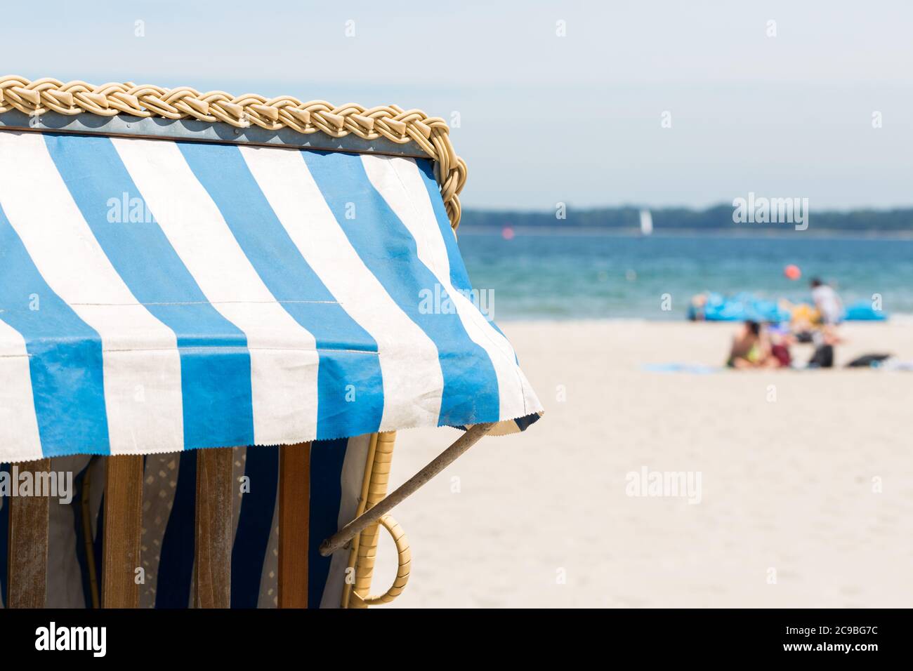 Détail d'un Strandkorb (chaise de plage en osier). La plage, la mer Baltique et les touristes en arrière-plan. Banque D'Images