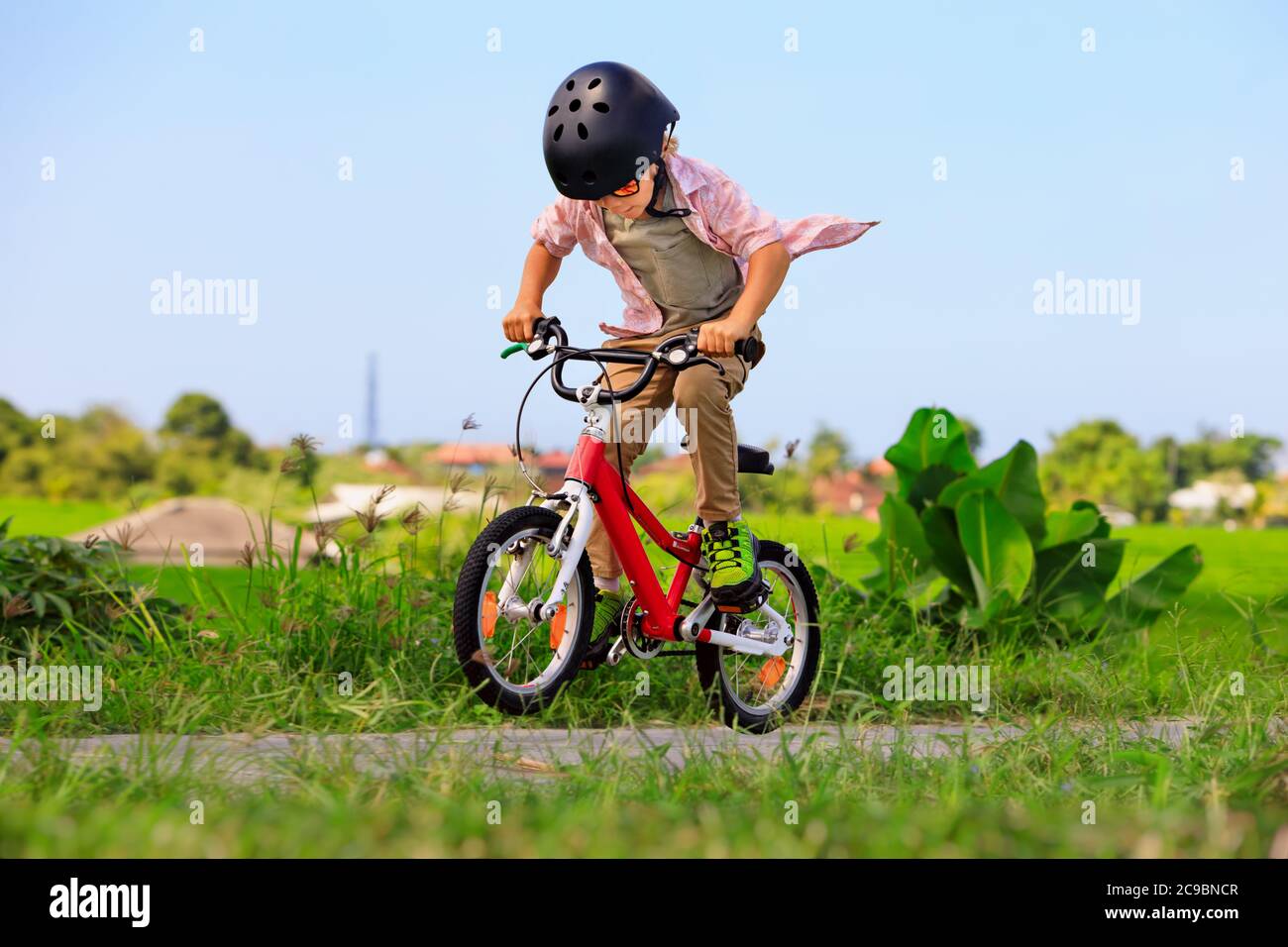 Randonnée à vélo. Jeune rider enfant dans un casque et des lunettes de soleil à vélo. Un enfant heureux s'amuse sur un sentier vide. Vie familiale active, sports Banque D'Images
