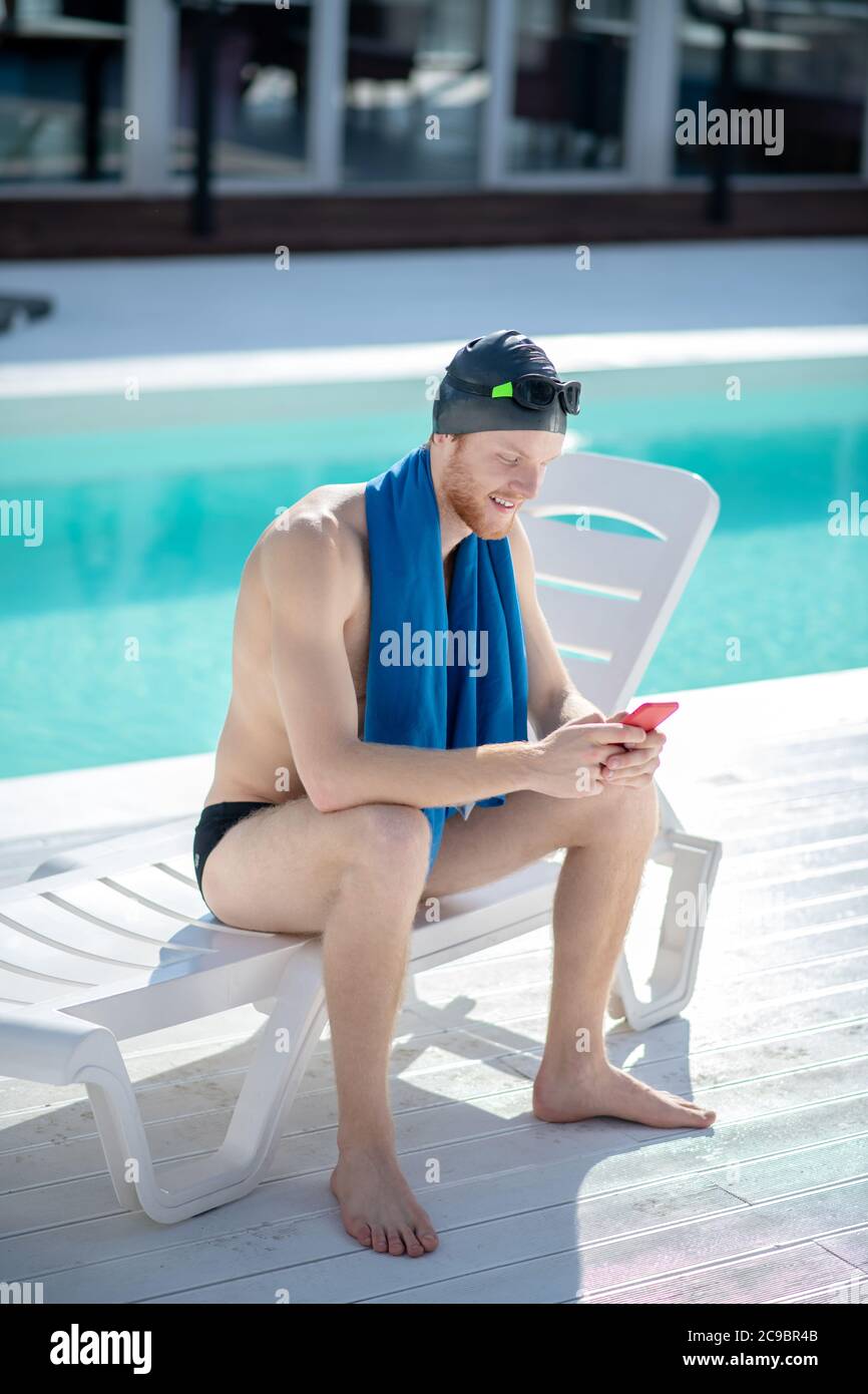 Homme dans la casquette de natation avec une serviette regardant le  smartphone Photo Stock - Alamy