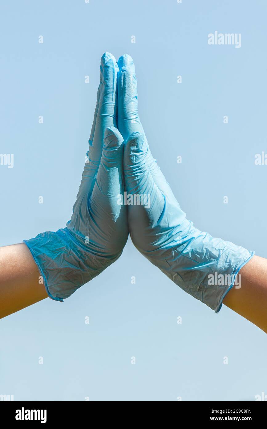 Deux mains avec un gant bleu claque le ciel bleu Banque D'Images