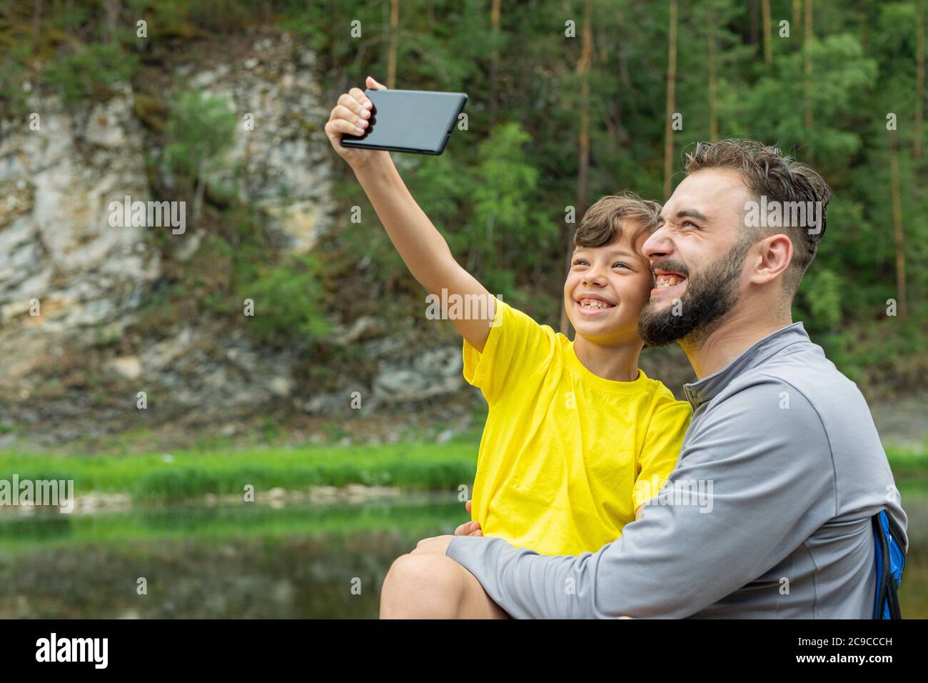 Papa et son fils font des photos sur smartphone en été dans la nature. Banque D'Images