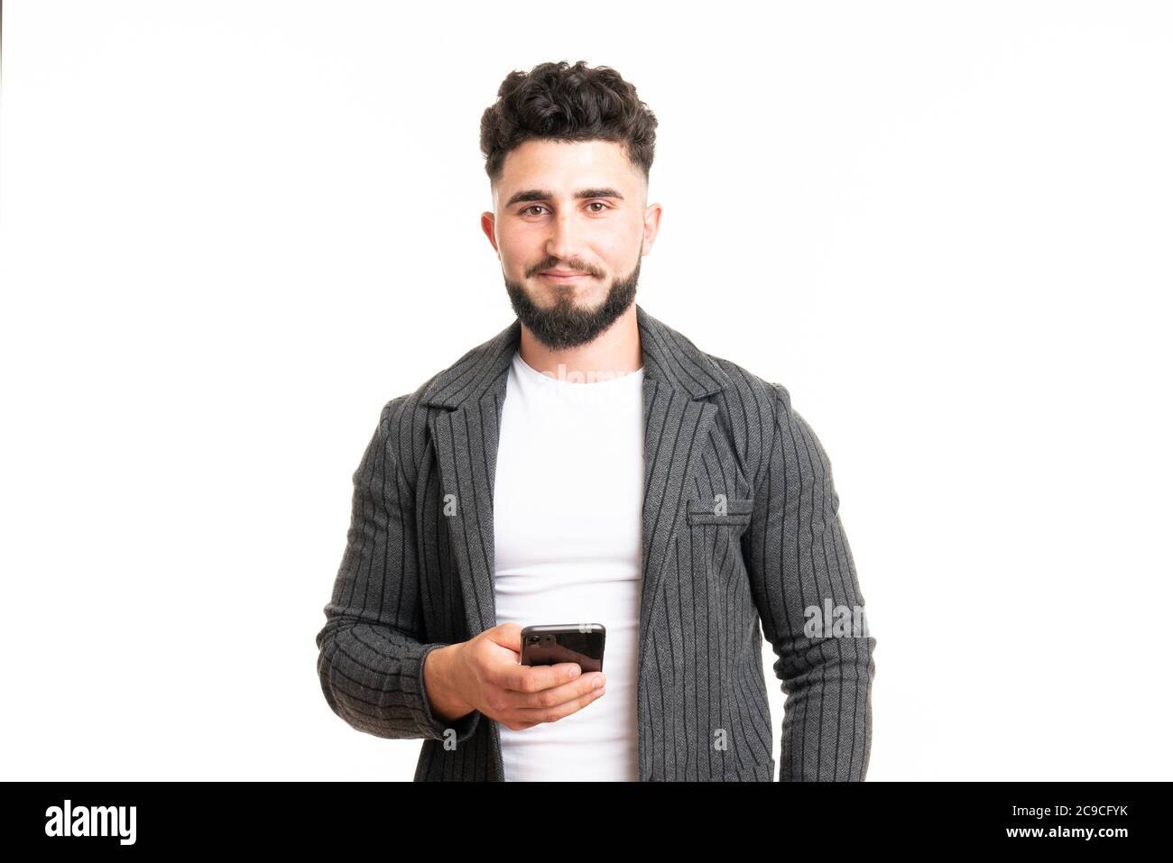 Un homme américain européen positif avec le sourire, tient un téléphone portable moderne, saisit des messages texte et des commentaires, surfume les réseaux sociaux, se réjouit de la haute vitesse Banque D'Images