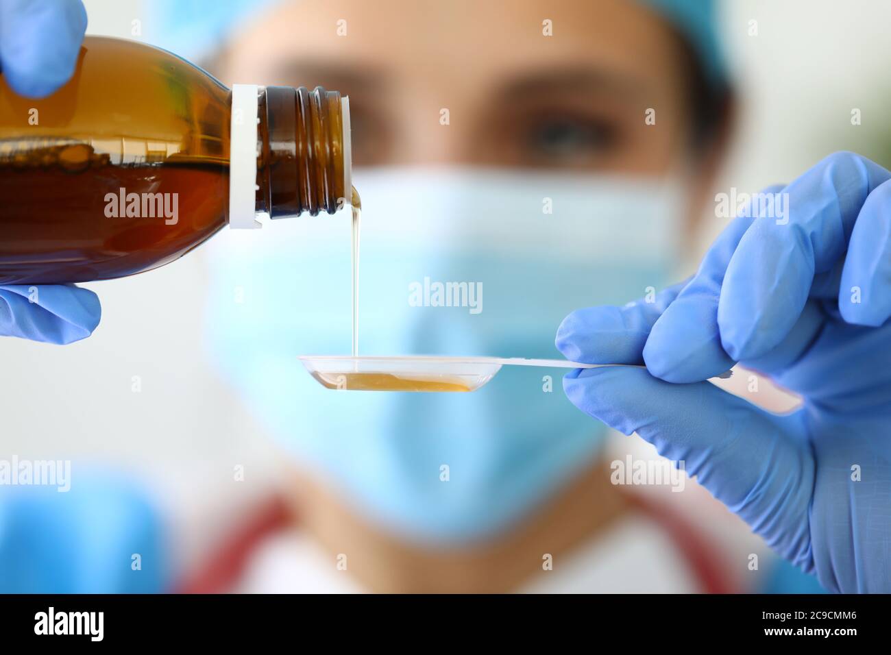L'infirmière verse du sirop froid médicamenteux dans une cuillère en plastique. Banque D'Images