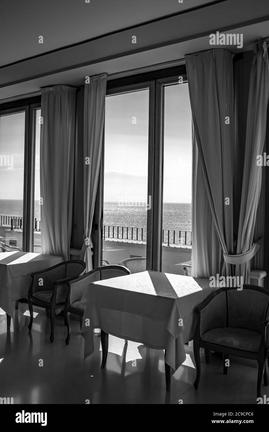 Les tables d'un hôtel avec une vue splendide sur la mer de la fenêtre. La lumière entre par la fenêtre le jour de l'été. Vacances, détente, luxe, Banque D'Images