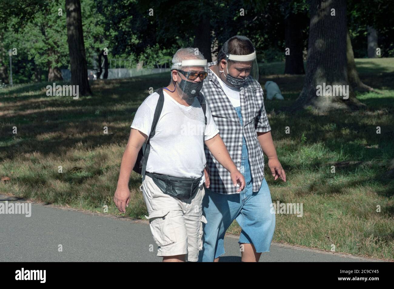 2 hommes asiatiques américains faire de l'exercice dans un parc wein9masques faciaux et écrans faciaux. À Flushing, Queens, New York Banque D'Images