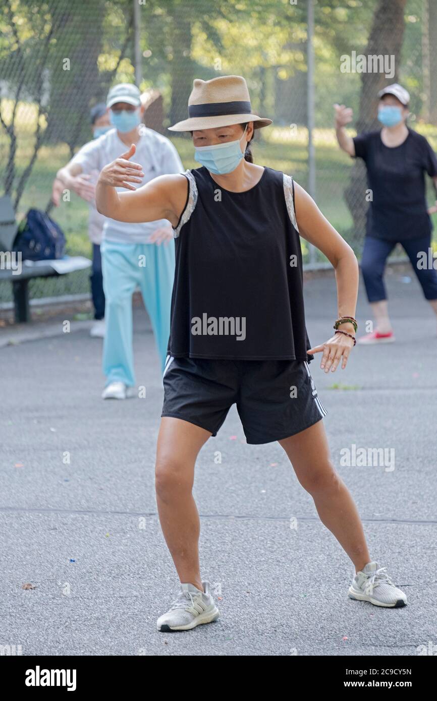 Des hommes et des femmes de divers âges et origines ethniques assistent à un cours de Tai Chi matinal, prennent des distances sociales et portent des masques chirurgicaux. Dans le Queens, New York. Banque D'Images