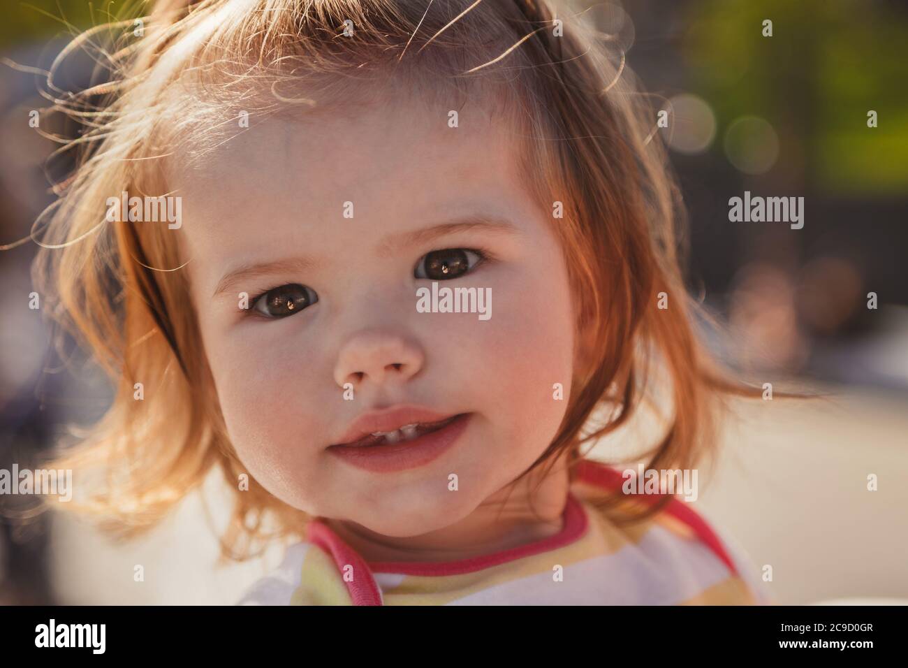 Gros plan portrait de beau petit bébé, blonde petite fille en pull coloré dans le parc à l'extérieur Banque D'Images