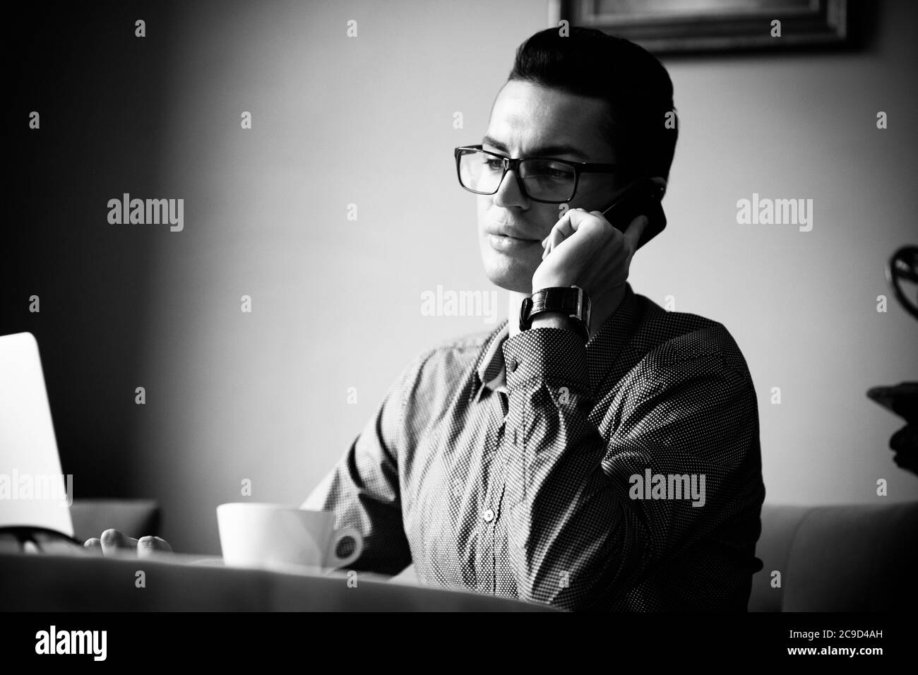 Concept de style de vie communautaire LGBT. Un jeune homosexuel est assis à la table dans un café de la ville à l'ancienne. Beau homme d'affaires gay parle au téléphone Banque D'Images