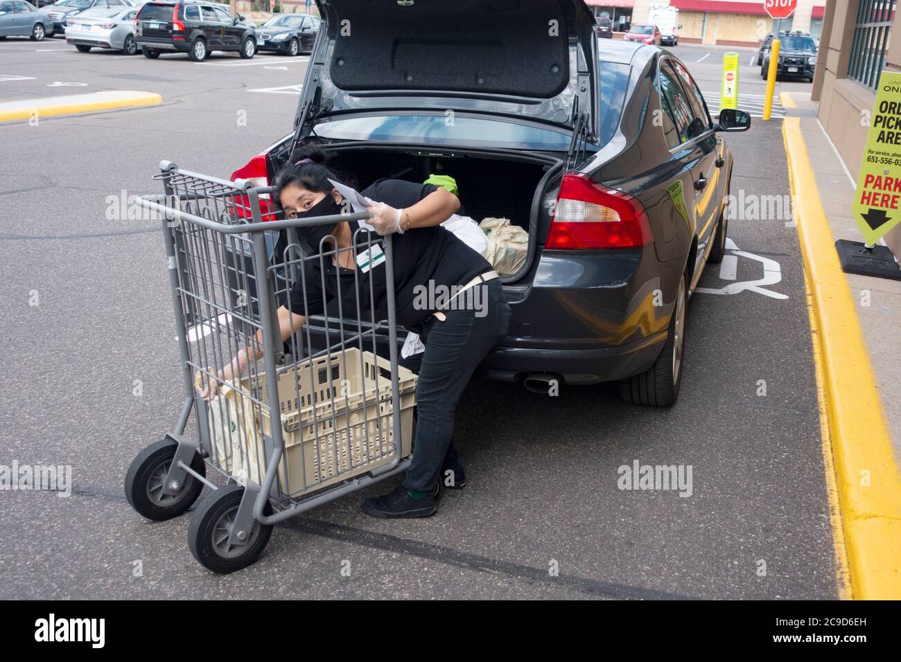 Femme livrant des articles d'épicerie sur le trottoir au magasin Lunds & Byerlys portant un masque et observant les distances sociales. St Paul Minnesota MN États-Unis Banque D'Images