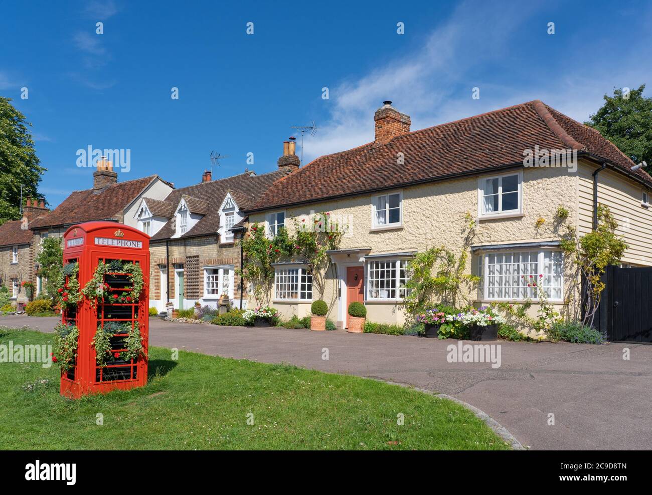 Décor traditionnel de village anglais avec maisons anciennes et ancien téléphone décoré de fleurs en premier plan. Standon, Hertfordshire. ROYAUME-UNI Banque D'Images