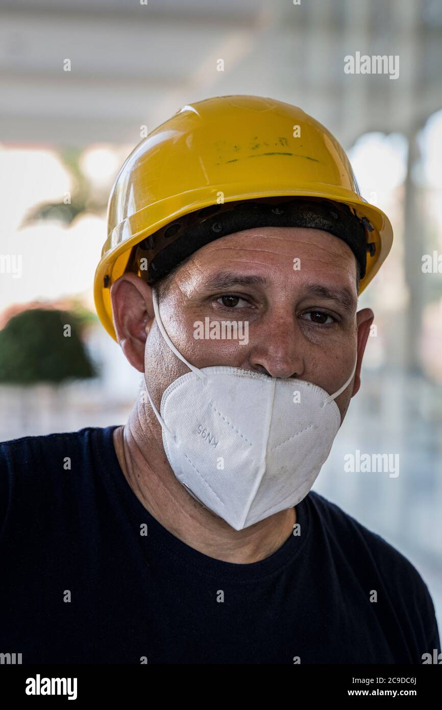 Les ouvriers de la construction portant des casques durs jaunes et des masques faciaux travaillent à la rénovation d'un hôtel à Costa Adeje à la suite du Covid 19 L. Banque D'Images