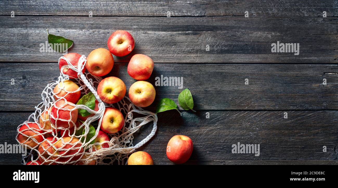 Sac à ficelle et pomme rouge sur fond en bois. Pommes mûres sur table et espace de copie vintage. Saison d'été ou d'automne. Banque D'Images