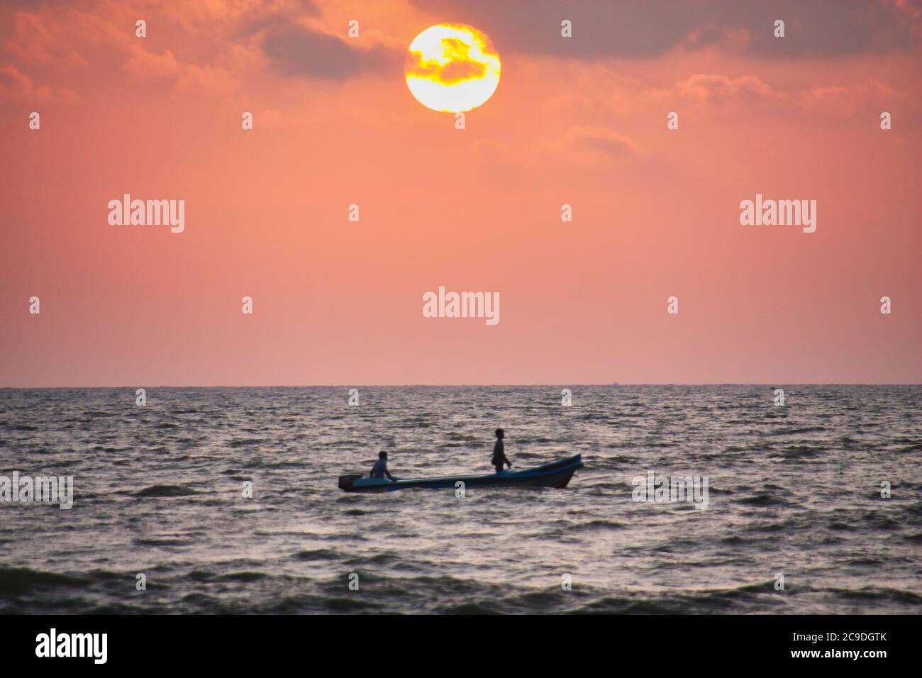 deux pêcheurs en bateau sur l'océan au coucher du soleil Banque D'Images