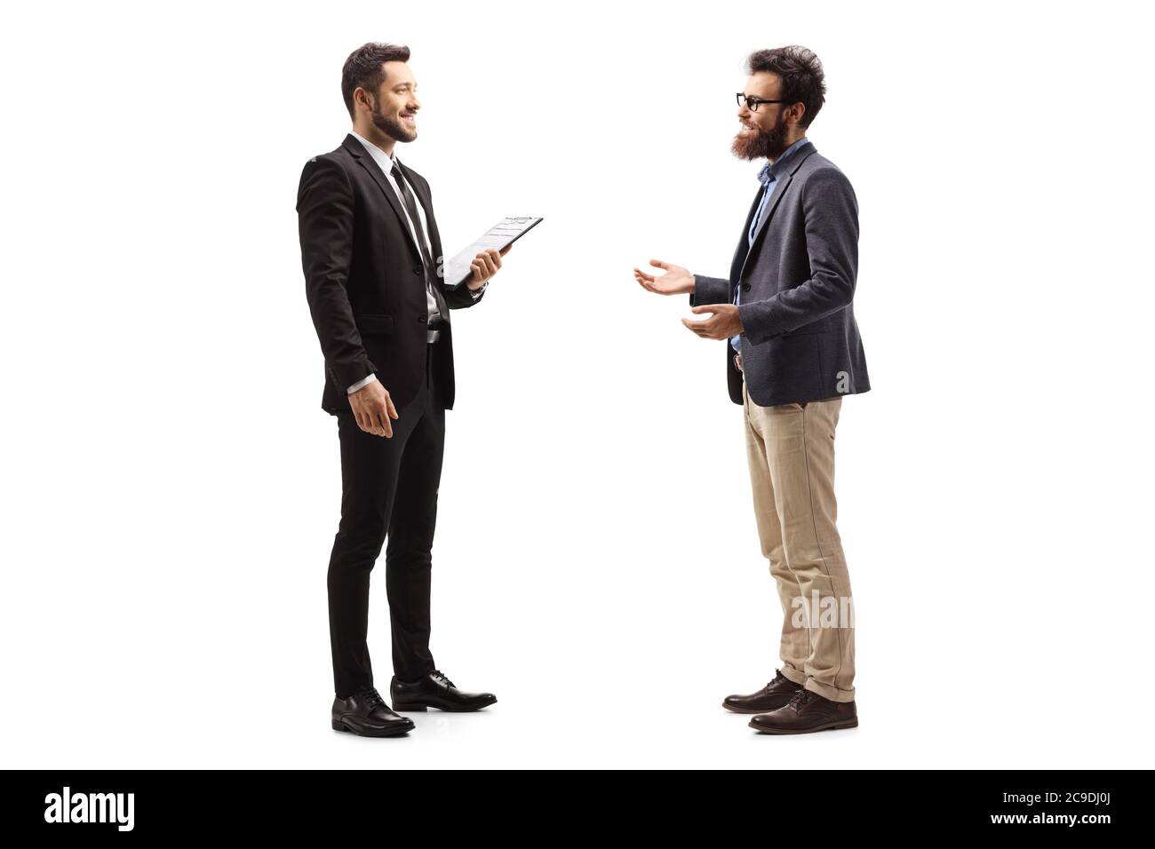 Photo de profil pleine longueur de deux jeunes hommes dans des vêtements formels parlant isolé sur fond blanc Banque D'Images