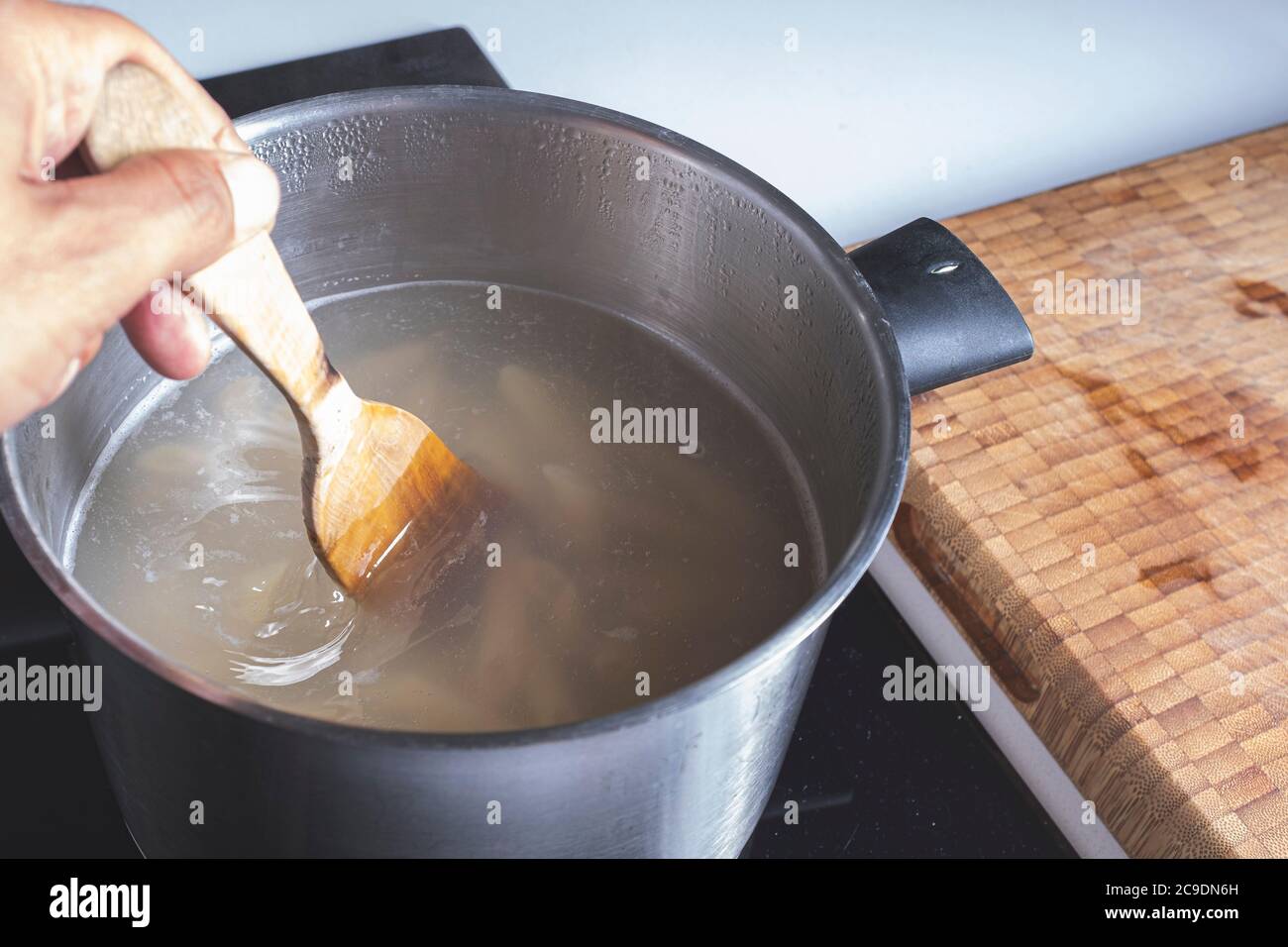 Mélanger les pâtes dans de l'eau chaude dans un pot d'argent avec une  cuillère en bois Photo Stock - Alamy