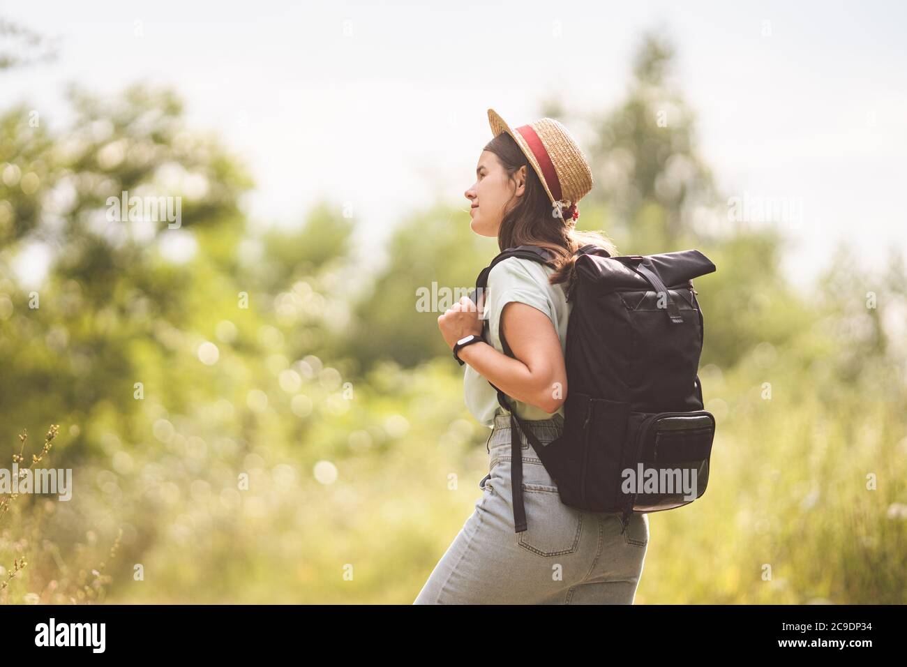 Chic taille basse fille en chapeau de paille voyage campagne. Jeune femme  avec sac à dos pour explorer et marcher dans le parc naturel d'été. Concept  de voyage et Photo Stock -
