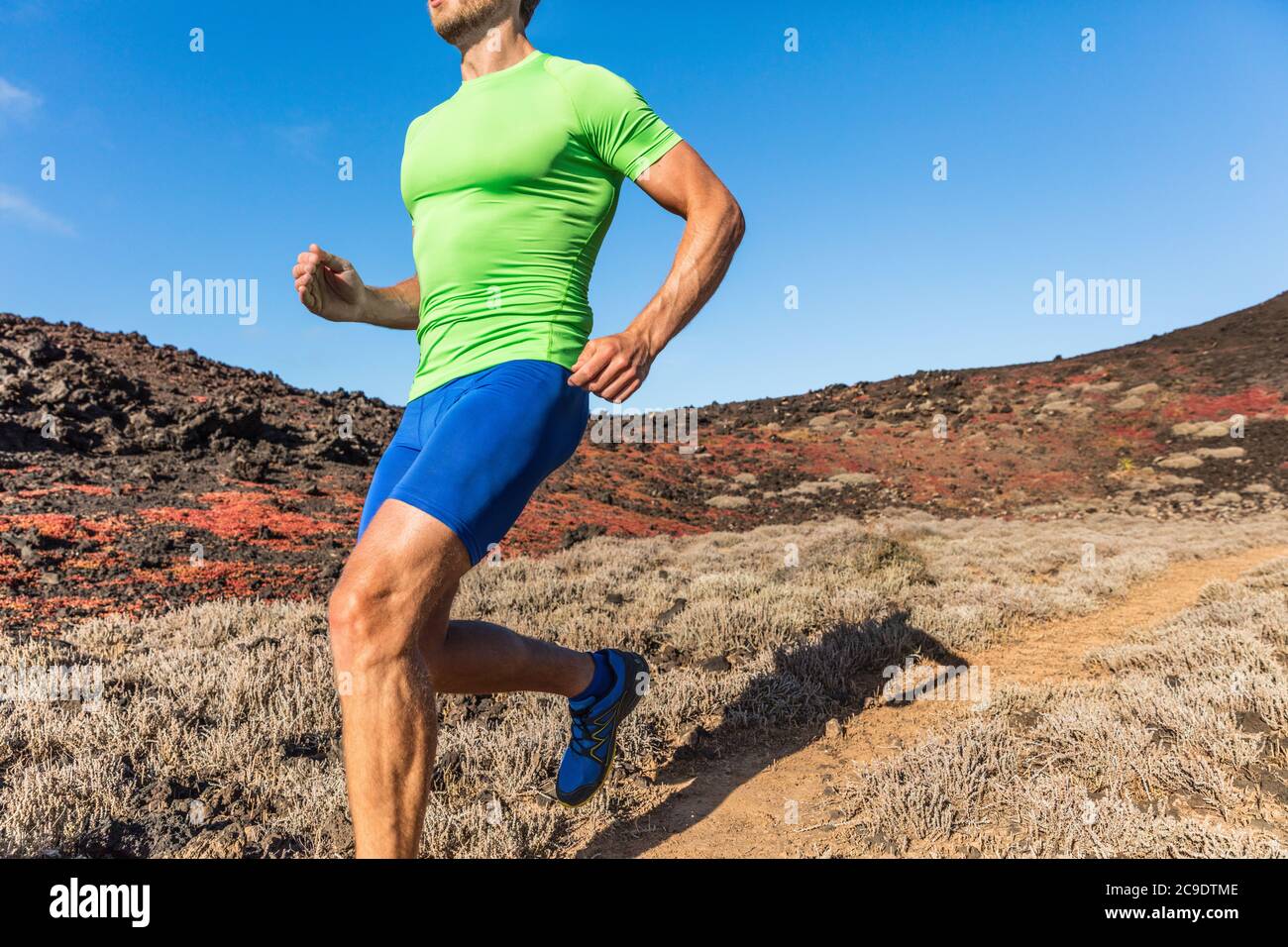 Coureur de piste homme de course ultra athlète sur le chemin du désert dans un paysage de chaleur sèche. Homme sportif personne entraînement à l'extérieur. Gros plan du corps et des jambes. Banque D'Images