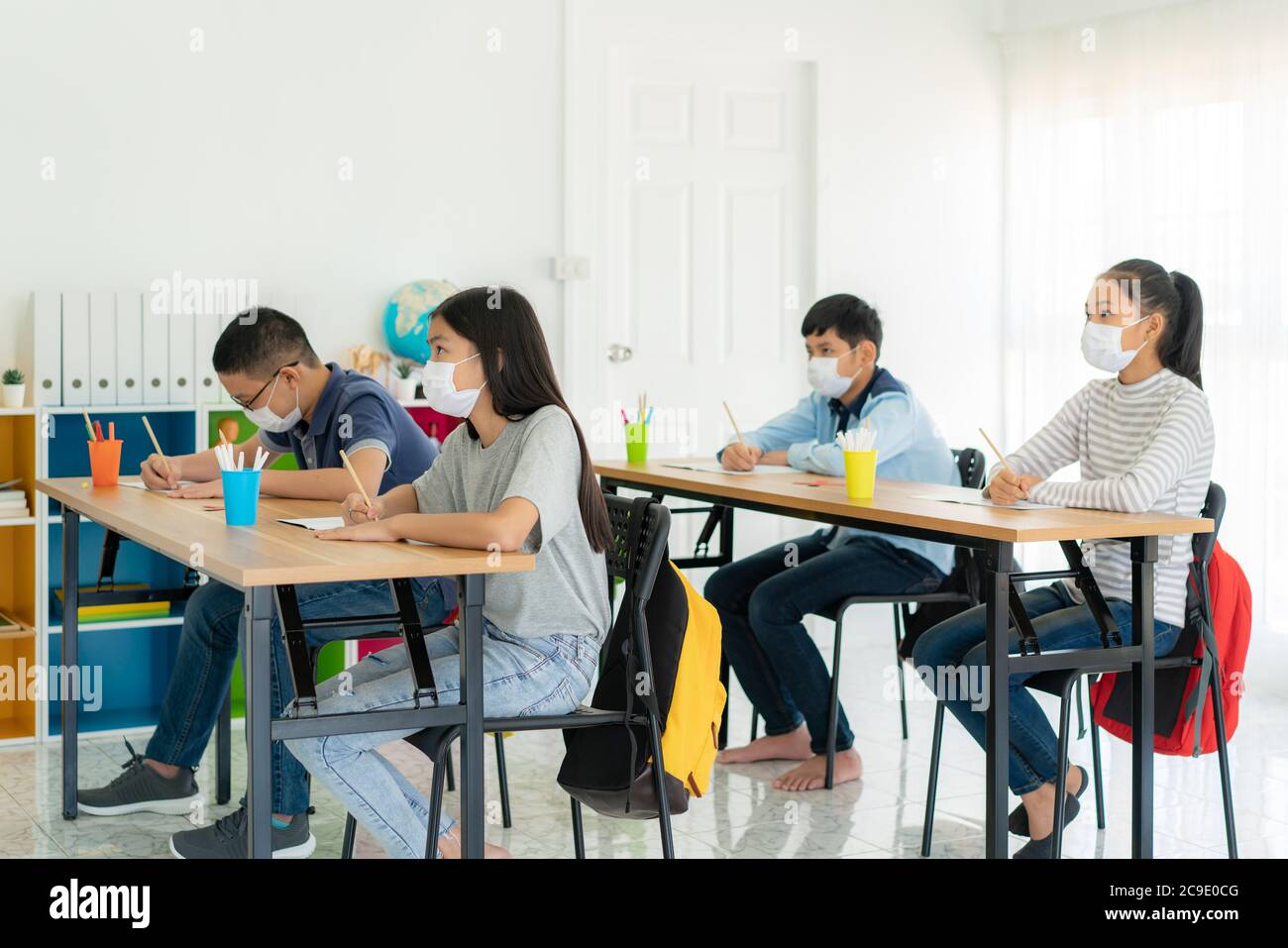 Groupe d'élèves asiatiques du primaire portant un masque hygiénique pour prévenir l'éclosion de Covid 19 en classe pendant leur rentrée rouvrir leur ppb Banque D'Images