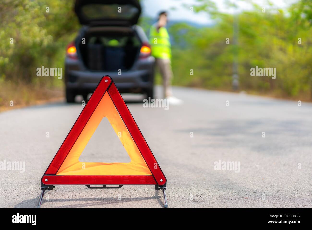 Triangle de signalisation sur route avec un homme asiatique inquiet parlant par téléphone mobile avec compagnie d'assurance ou de centre de service de voiture après la panne de voiture sur cou Banque D'Images Triangle de signalisation sur route avec un homme asiatique inquiet parlant par téléphone mobile avec compagnie d'assurance ou de centre de service de voiture après la panne de voiture sur cou Banque D'Images