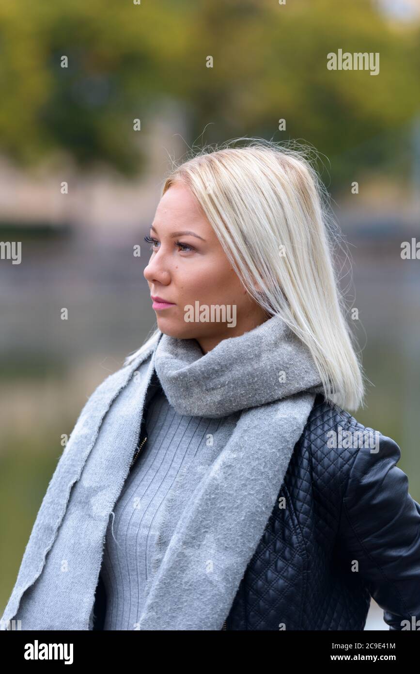 Jeune belle femme blonde pensant contre la vue floue de la rivière Banque D'Images