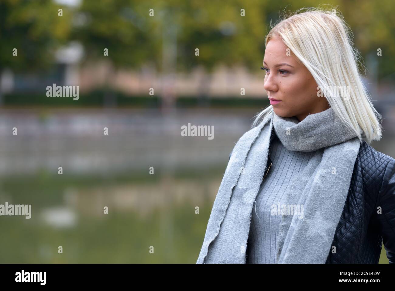 Jeune belle femme blonde pensant dans le parc le long de la rivière Banque D'Images