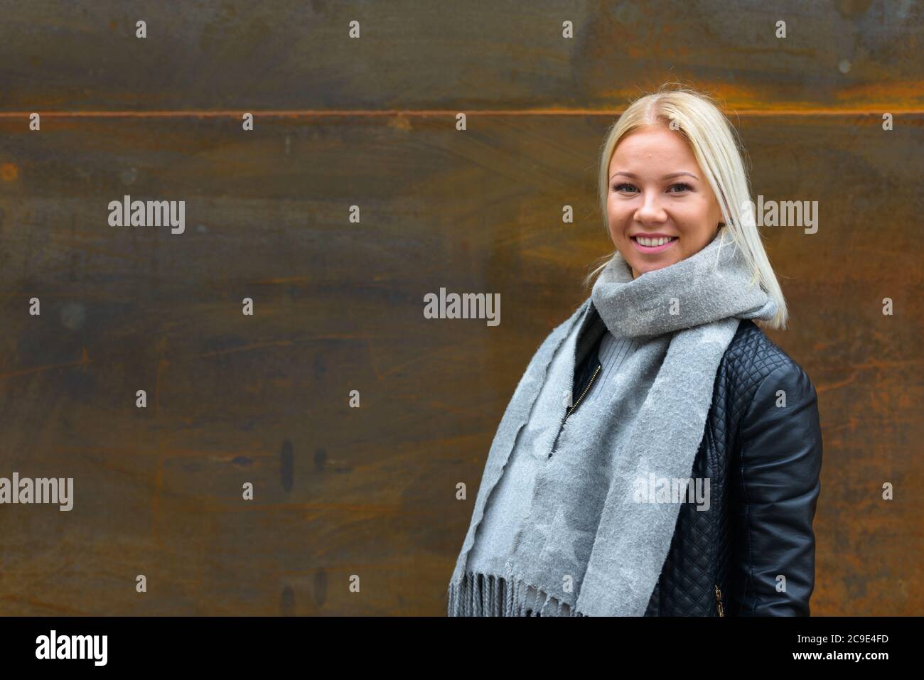 Bonne jeune belle femme blonde souriante contre vieux mur en métal rouillé Banque D'Images