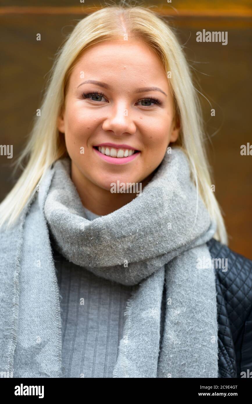 Bonne jeune belle femme blonde souriante contre vieux mur en métal rouillé Banque D'Images