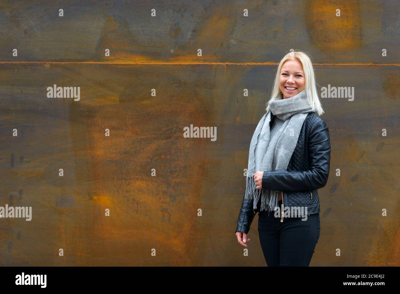 Bonne jeune belle femme blonde souriante contre vieux mur en métal rouillé Banque D'Images