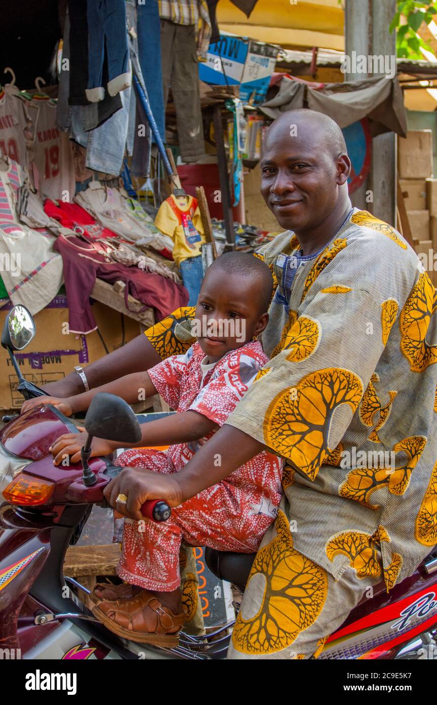 Scène de rue avec un père et son fils sur un scooter à moteur dans le centre-ville de Bamako, la capitale et la plus grande ville du Mali. Banque D'Images