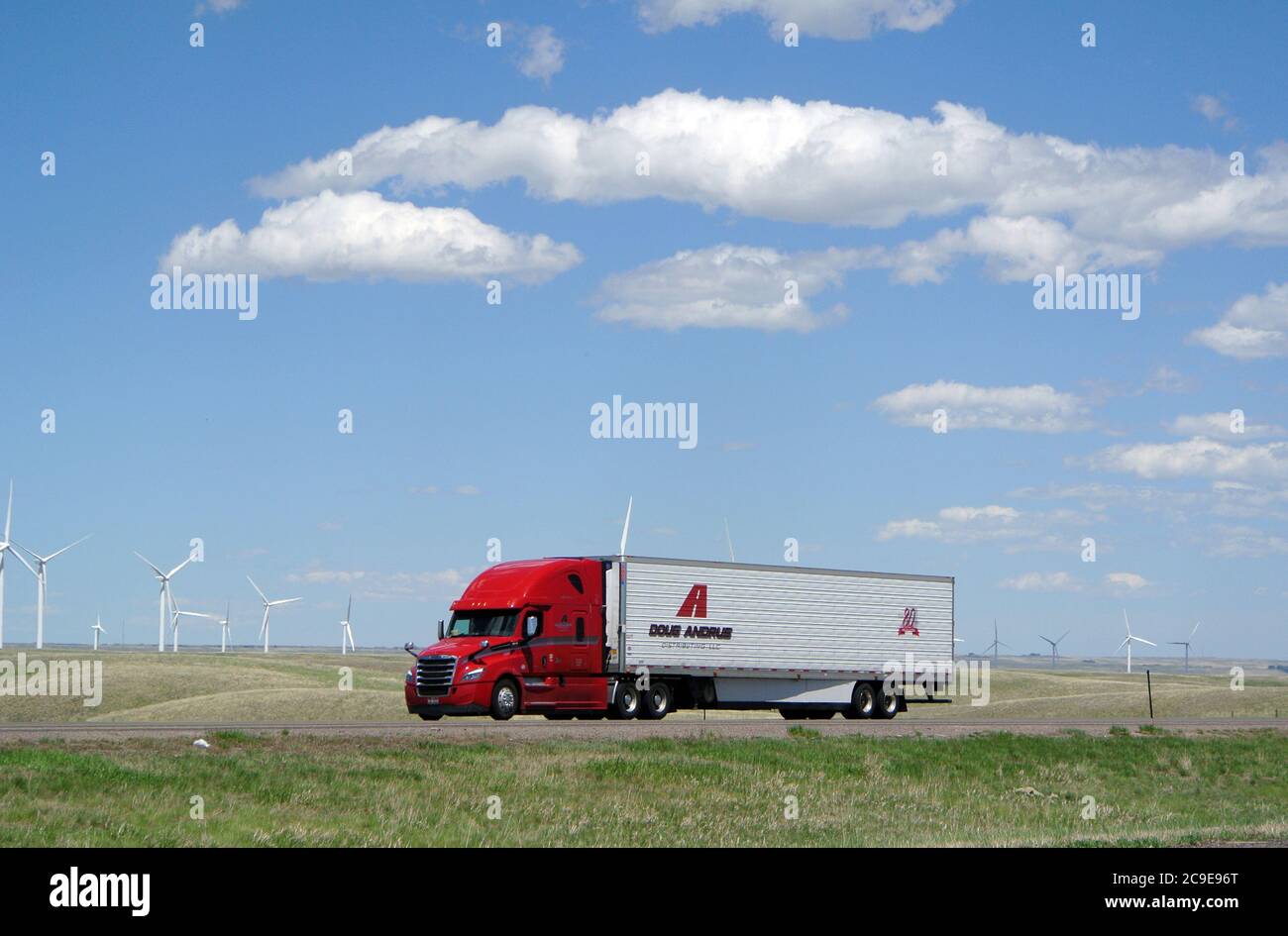 le camion-remorque rouge se déplace sur l'i 90 en panoramique wyoming états-unis paysage avec moulins à vent Banque D'Images
