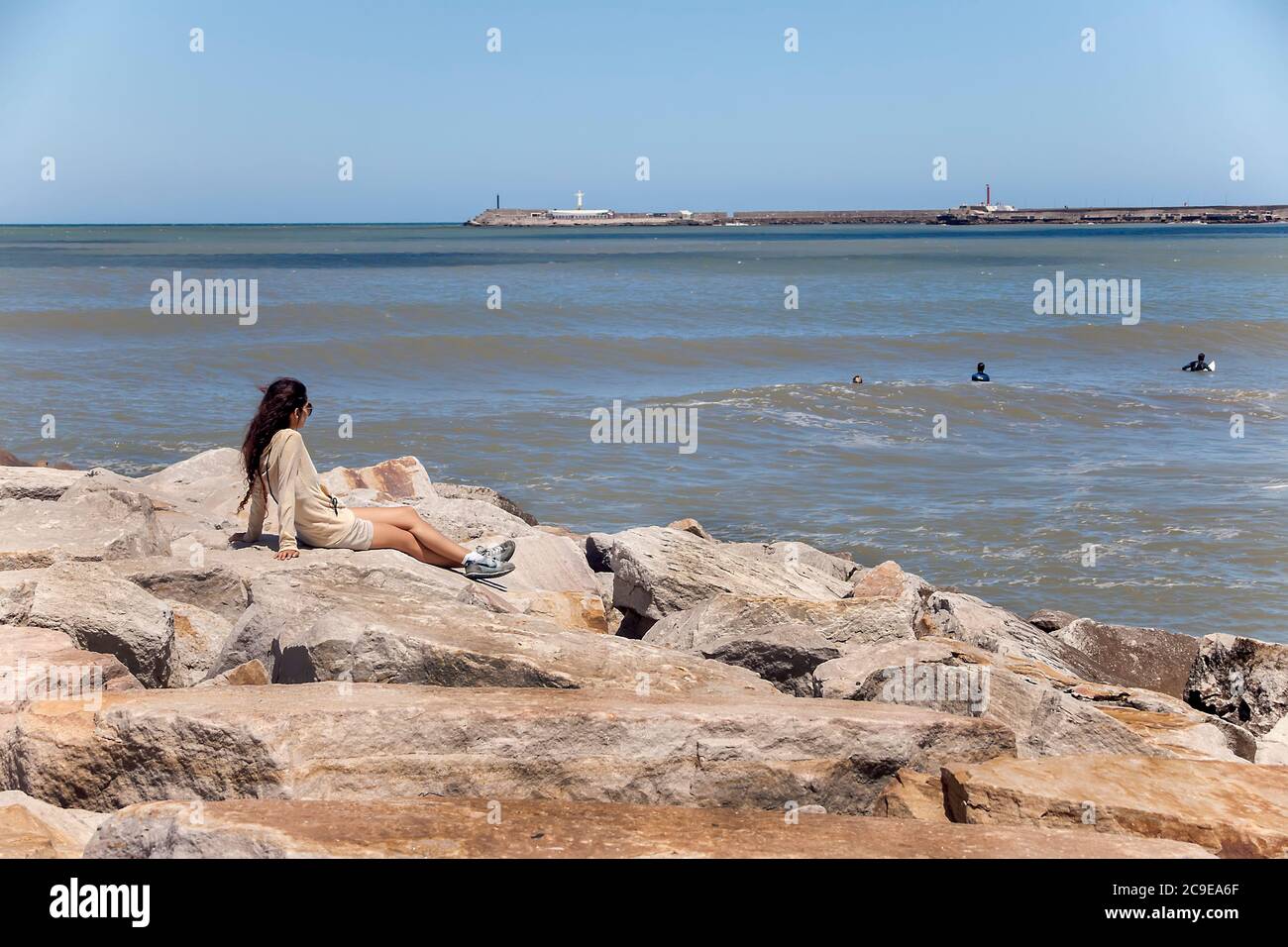 Femme sur le brise-lames regardant les surfeurs dans la mer au large de Mar del Plata, province de Buenos Aires, Argentine Banque D'Images