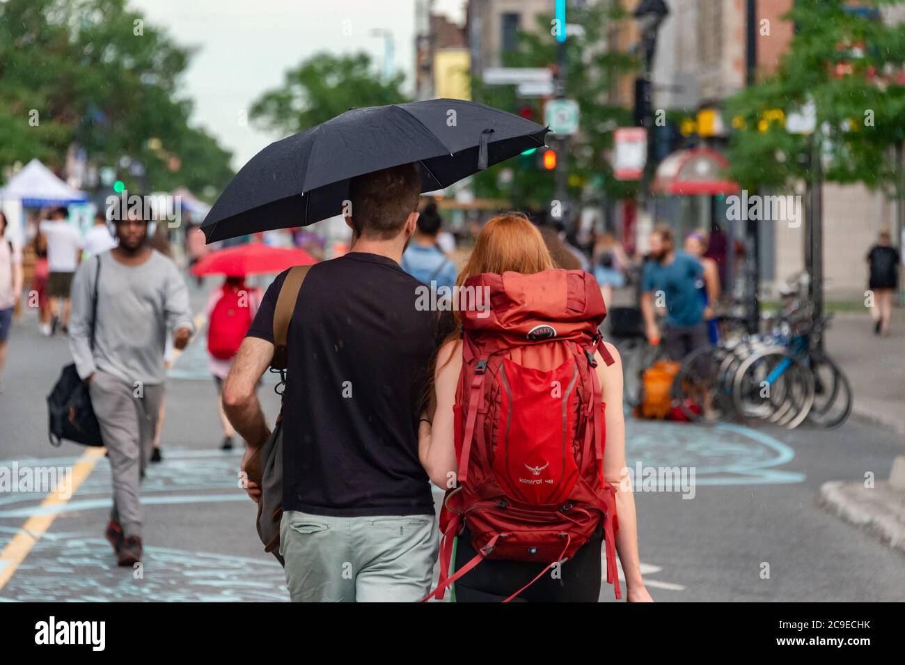 Montréal, CA - 30 juillet 2020 : couple sur l'avenue Mont-Royal tenant un parapluie sous la pluie et la tempête Banque D'Images