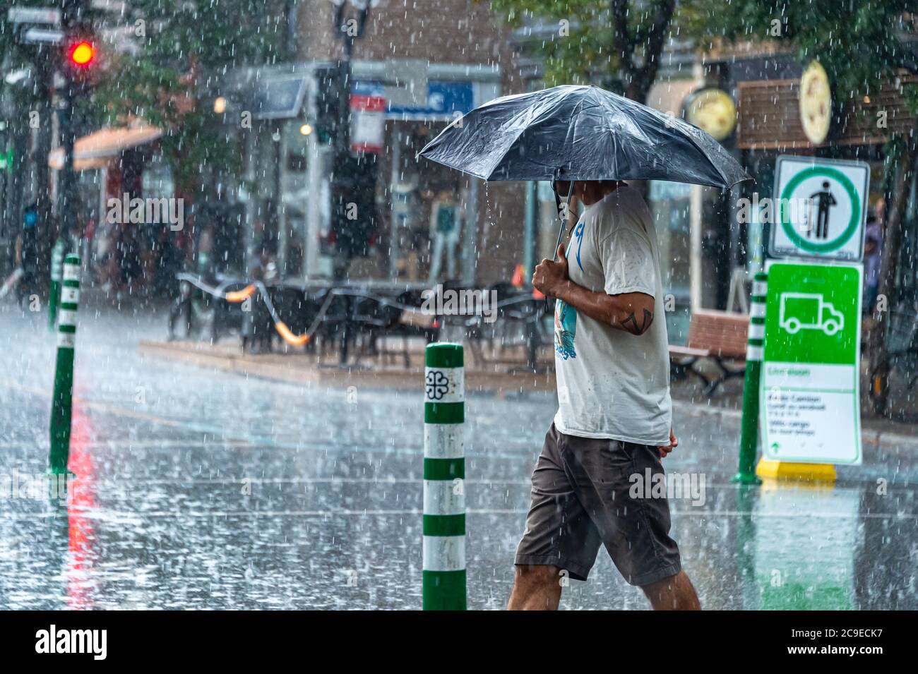 Montréal, CA - 30 juillet 2020 : un homme sur l'avenue Mont-Royal tenant un parapluie sous la pluie et la tempête Banque D'Images