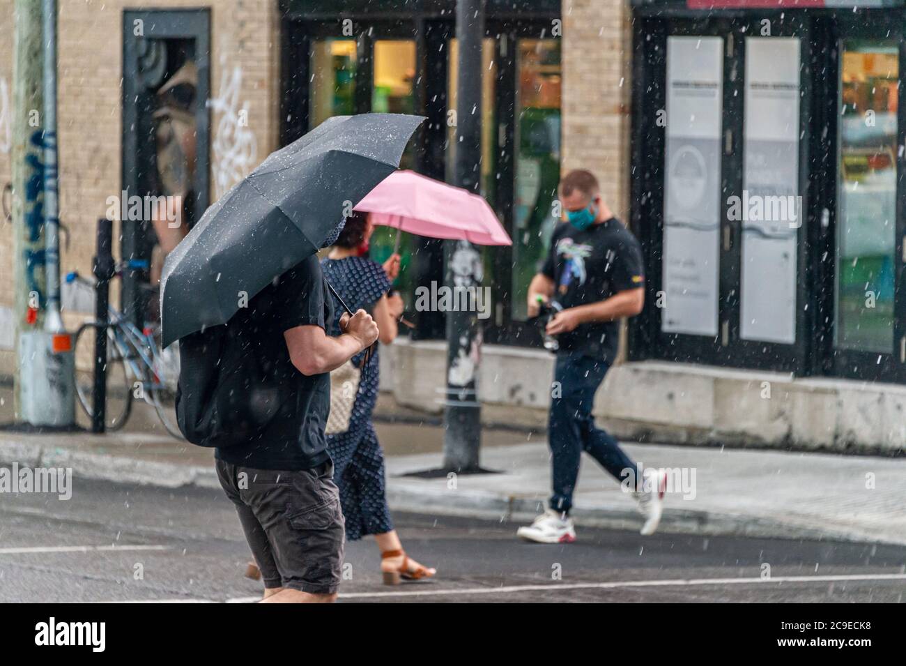 Montréal, CA - 30 juillet 2020 : personnes sur l'avenue Mont-Royal tenant des parasols sous la pluie et la tempête Banque D'Images