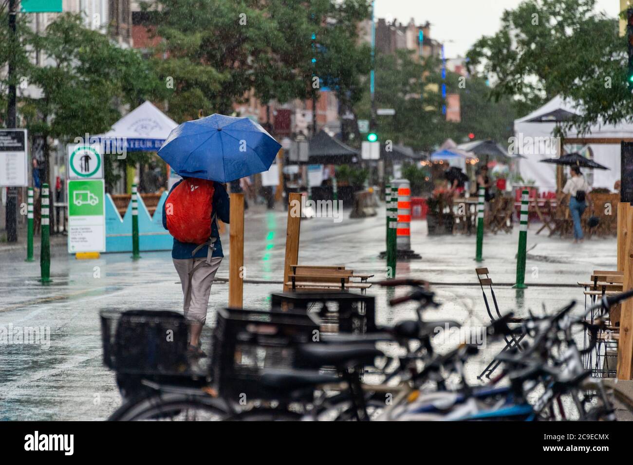 Montréal, CA - 30 juillet 2020 : femme sur l'avenue Mont-Royal tenant un parapluie sous la pluie et la tempête Banque D'Images