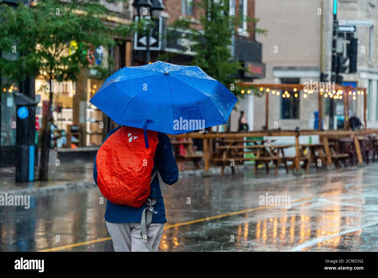 Montréal, CA - 30 juillet 2020 : femme sur l'avenue Mont-Royal tenant un parapluie sous la pluie et la tempête Banque D'Images