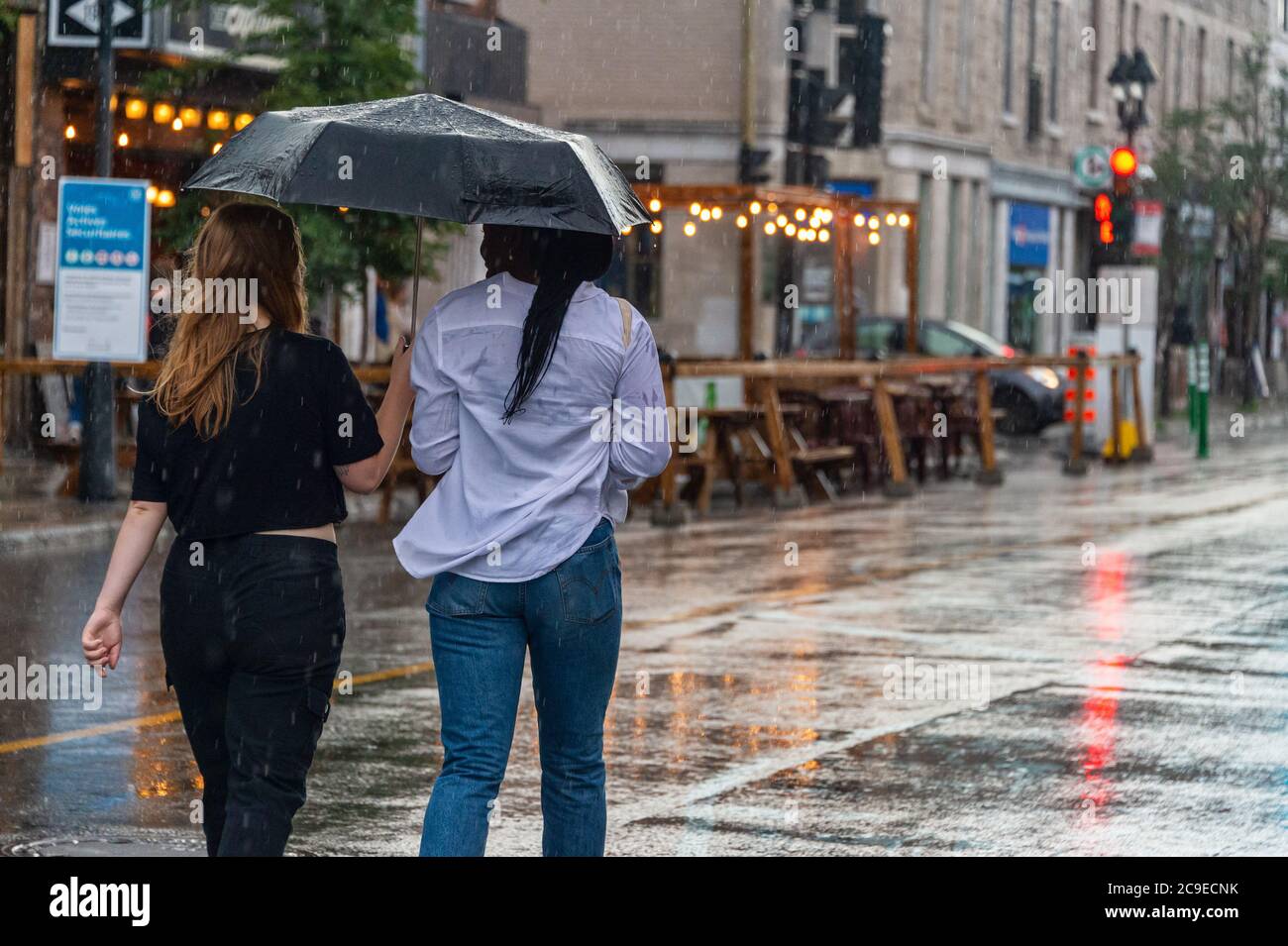 Montréal, CA - 30 juillet 2020 : personnes sur l'avenue Mont-Royal tenant un parapluie sous la pluie et la tempête Banque D'Images