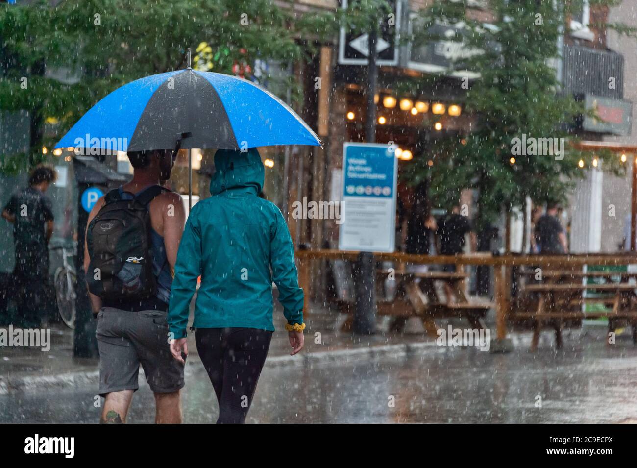 Montréal, CA - 30 juillet 2020 : personnes sur l'avenue Mont-Royal tenant un parapluie sous la pluie et la tempête Banque D'Images