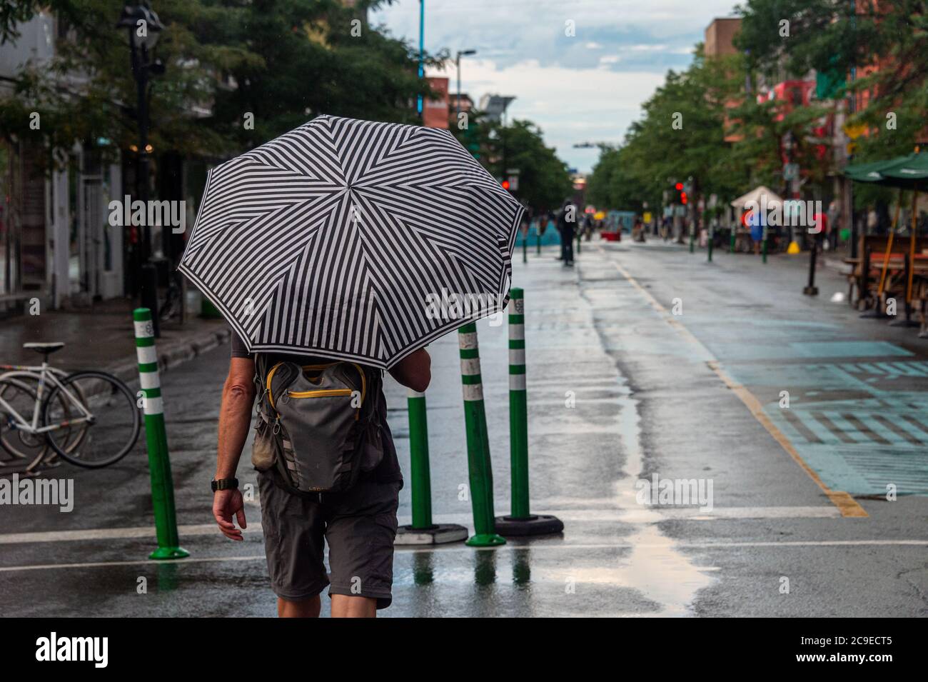 Montréal, CA - 30 juillet 2020 : un homme sur l'avenue Mont-Royal tenant un parapluie sous la pluie et la tempête Banque D'Images